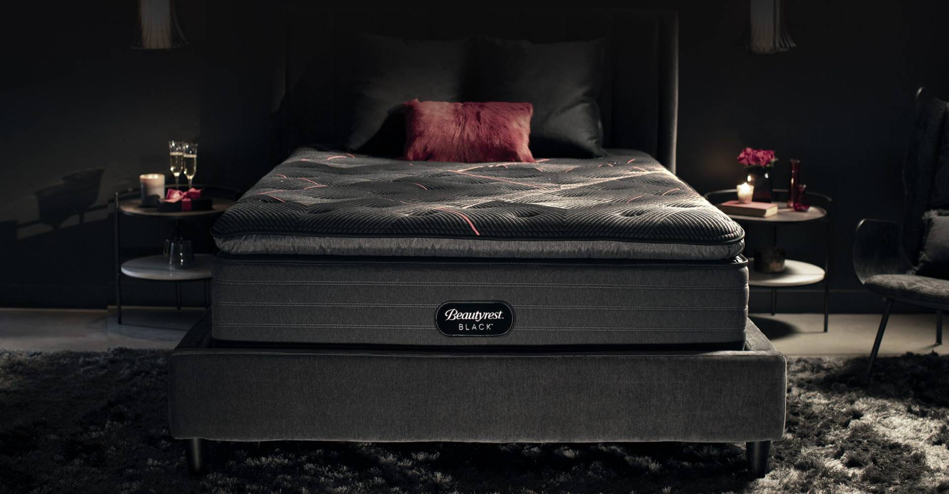 Beautyrest Black mattress in a candlelit bedroom with two glasses of champagne on the bedside table.